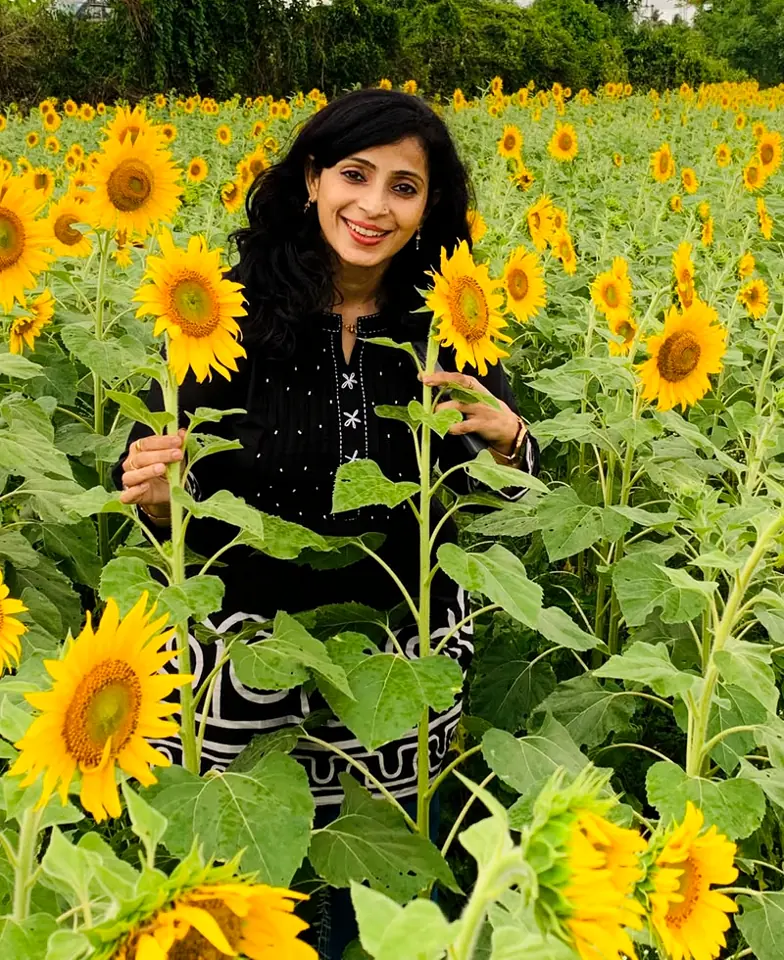Dr. Reena Soni smiling in a field of sunflowers